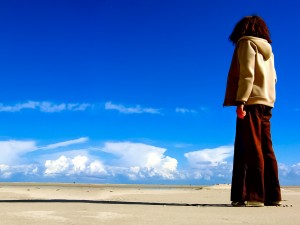 Frau am einsamen Strand schaut in die Ferne
